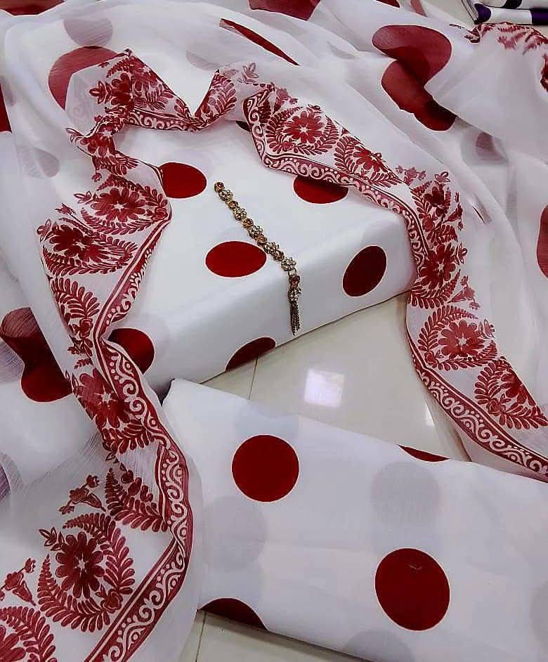 White fabric with red polka dots and intricate patterns on a tiled floor.