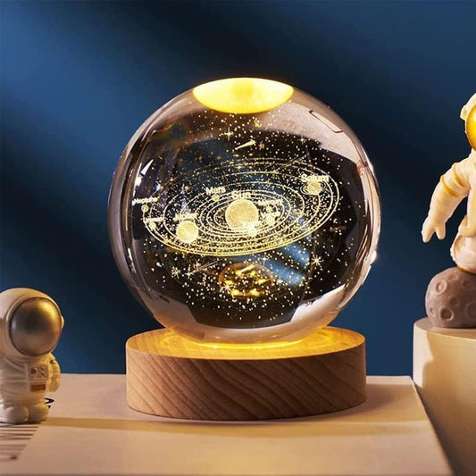 Glass ball with solar system model on a wooden base against a dark blue background