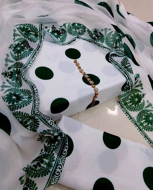 White fabric with green polka dots and black patterns on a white background